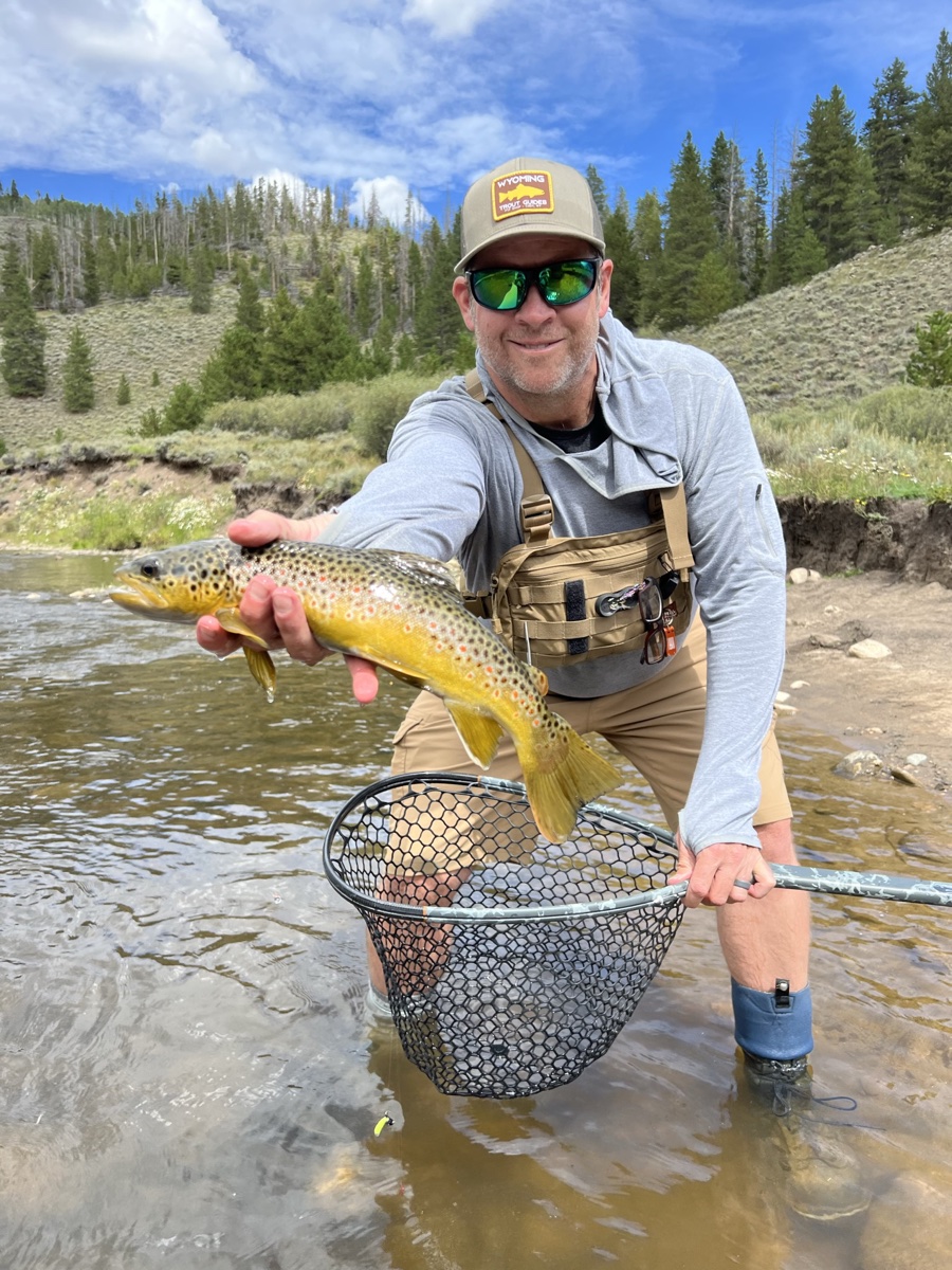 Ed, owner and guide at Drifters Fly Fishing, holding a brown trout in a Colorado mountain river