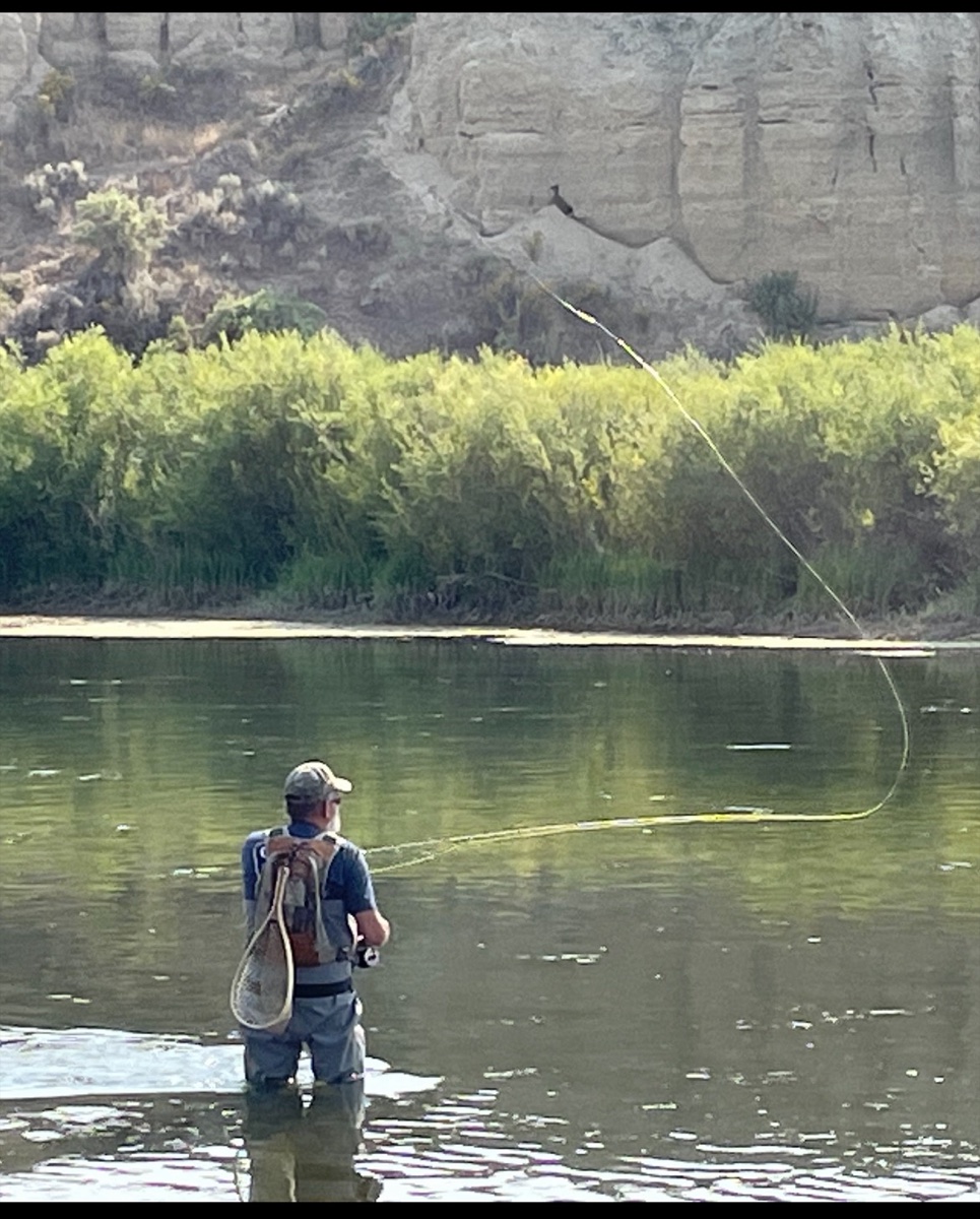 Angler casting a fly rod in a Colorado canyon river